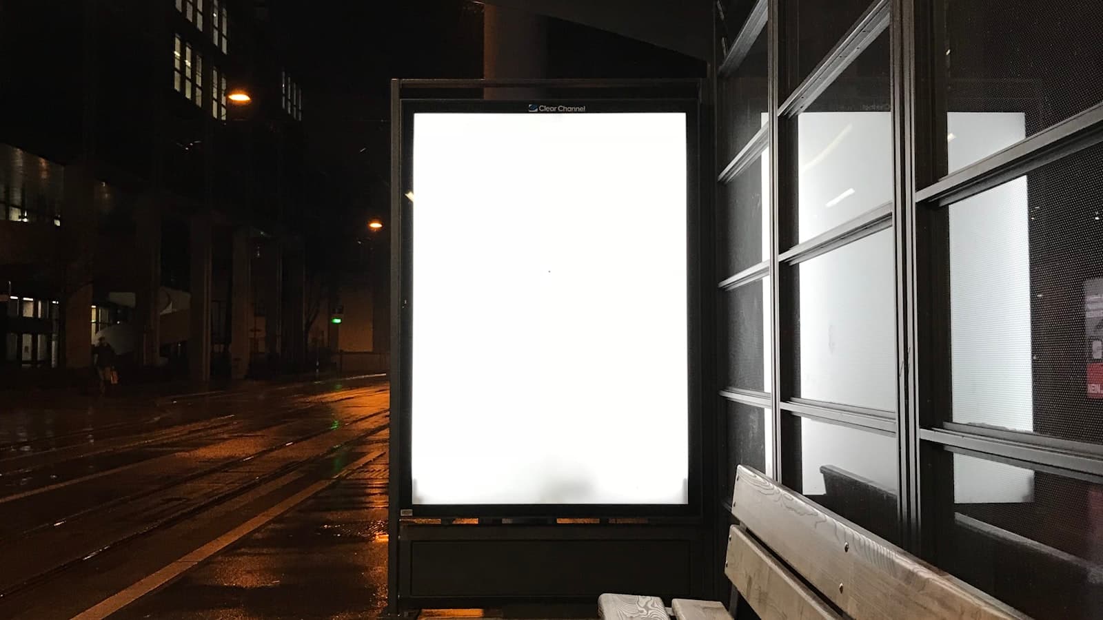 A blank illuminated advertising billboard on a city street at night